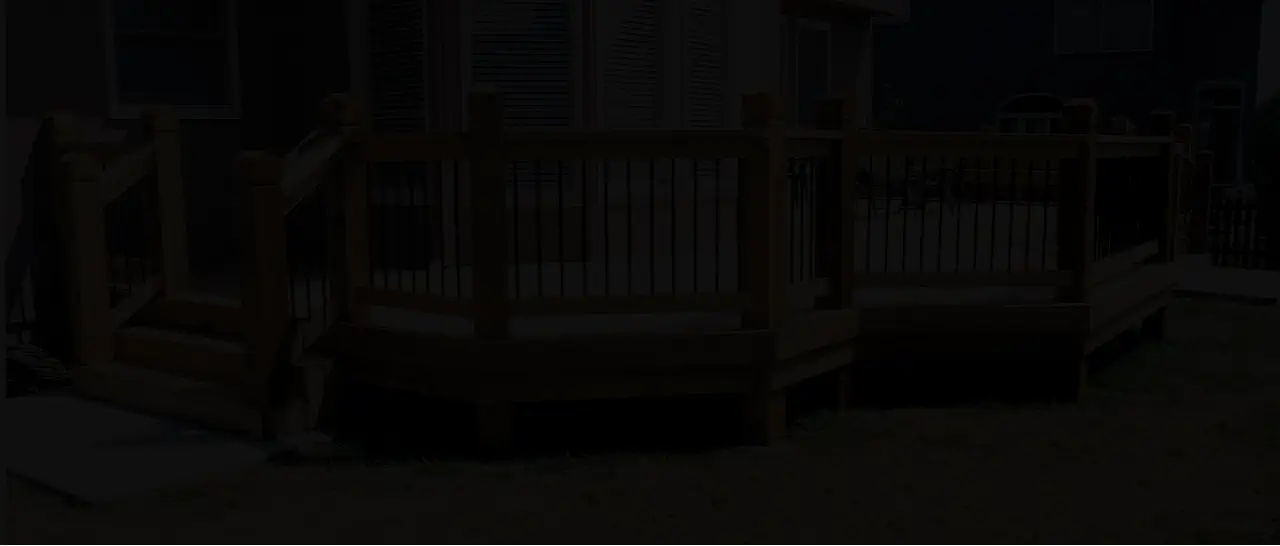 Custom wood deck with black metal railings built by Pro Deck & Design in Kansas City, showcasing nighttime ambiance and professional craftsmanship for safe outdoor living spaces in Johnson County homes